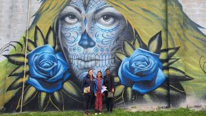 AAWCC members posing in front of the "Love is sacrifice" mural by Jeff Soto at the Rochester Public Market.