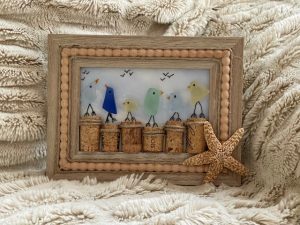 Sea glass rectangular frame with a star fish and multiple birds perched on a wine cork.