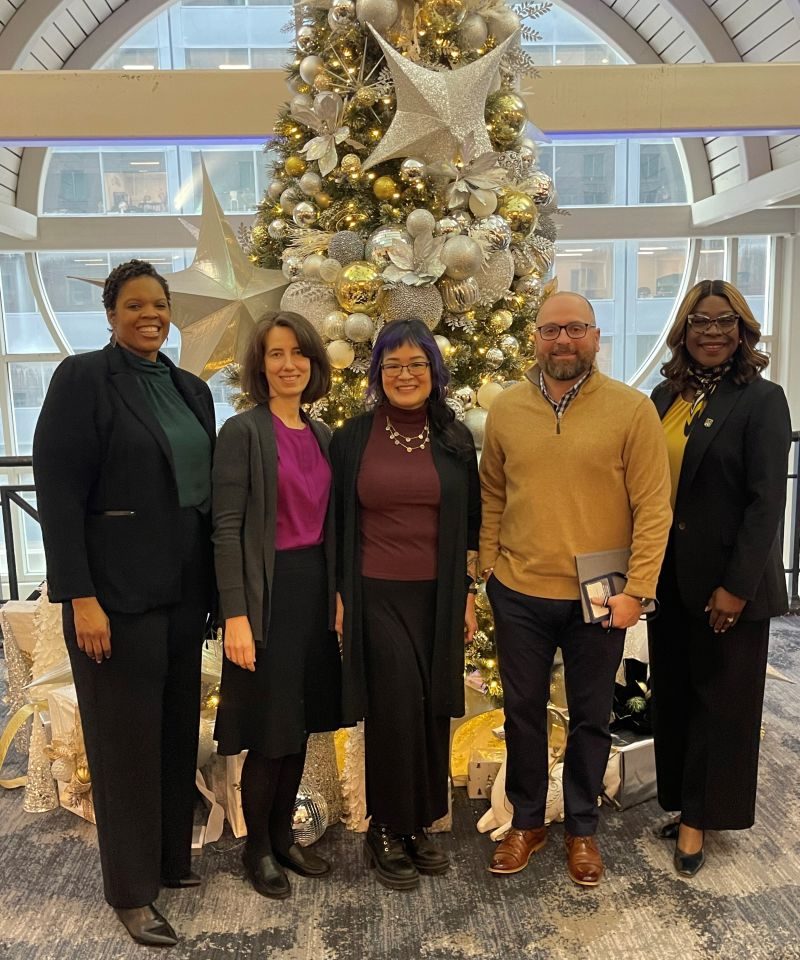 MCC Middle States representative from left to right: Candice Baldwin, Susan Hall, Natasha Chen, Mike Jacobs and President Burt-Nanna standing in front of a decorated holiday tree