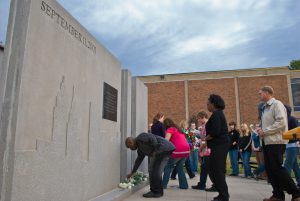 Attendees lay white carnations at the base of a memorial at MCC in honor of 9/11 victims.