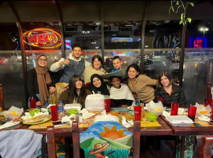 A group photo of the Financial Aid work study team gathered around a table after their monthly celebratory dinner.