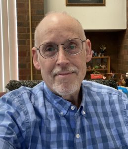 Headshot of Rick Squires looking directly into the camera wearing glasses and a blue dress shirt.