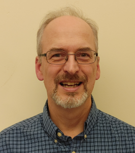 Head shot of Paul Seeburger smiling, wearing glasses, and a blue dress shirt.