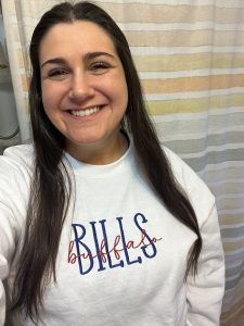 Headshot of Morganne Madonia smiling at the camera as she wears a Buffalo Bills shirt.