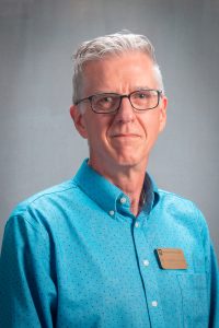Professional headshot of Dr. Andrew Knapp wearing a blue dress shirt and glasses.