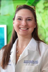 Professional headshot of Kristin Scheible, MD, wearing her lab coat and smiling at the camera.