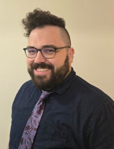 Professional headshot photo of Ben Schermerhorn wearing a dark dress shirt and tie as he smiles at the camera.