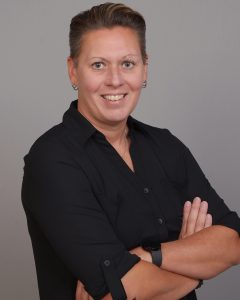 Angela Granger wearing a black shirt with her arms crossed as she smiles at the camera.
