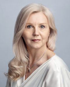 Professional headshot of Elena Dilai wearing an off-white blouse and necklace.