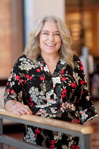 Christine Cormack leaning on a railing as she smiles at the camera.