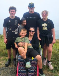 Melissa Gue, her husband, and their four children pose together outdoors.