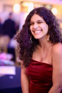 Photo of Stella with long curly hair wearing a strapless red dress 