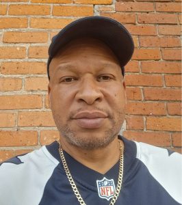 Joe Calhoun Jr. standing in front of a brick wall wearing an NFL jersey and hat.