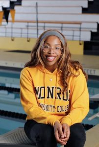 Jalisia Burno wearing a Monroe Community College sweatshirt as she sits in front of the College's pool.