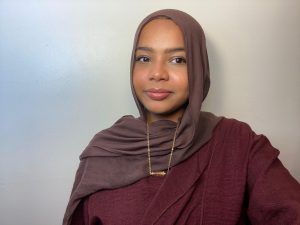  Basma Mohamed wearing a maroon hijab and gold necklace.
