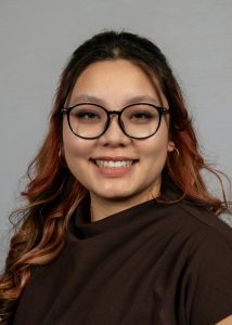 KhaNy Sangasy wearing black glasses and a brown shirt.