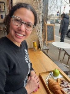 Melis Kural smiling at the camera with a tray of food in front of her.