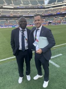 Kevin Messam stadium: Kevin in a suit, on the field with a fellow World Cup employee.