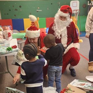 Phi Theta Kappa members dressed as Santa and his helpers give daycare children gifts for Christmas