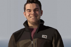 Digital image of a man from the waist up. He is wearing a coat and smiling at the viewer.