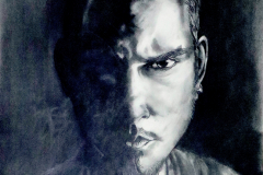 Charcoal drawing of the. artist , portrait in harsh lighting from the right of the face and the left being in light , many different marks made to change the illusion in the dark side of the portrait, heavy blacks and highlights.