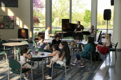 This image shows visitors to the gallery sitting at tables, and in the background a band is playing music.
