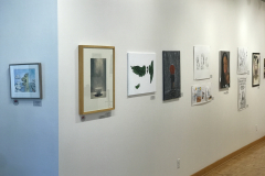 This is a photograph of the 44th annual student art exhibition installation. In this image we are seeing a small section of the left wall of the gallery with 10 pieces of art installed in the space.