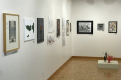This is a photograph of the 44th annual student art exhibition installation. In this image we are seeing the back left corner of the gallery with 14 pieces of art installed in the space.