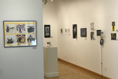 This is a photograph of the 44th annual student art exhibition installation. In this image we are seeing a small section of the right wall of the gallery with 12 pieces of art installed in the space.
