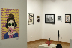 This is a photograph of the 44th annual student art exhibition installation. In this image we are seeing a small section of the rear right corner of the gallery with 8 pieces of art installed in the space.