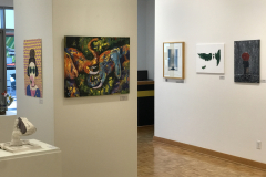 This is a photograph of the 44th annual student art exhibition installation. In this image we are seeing a small section of the left wall of the gallery with 6 pieces of art installed in the space.