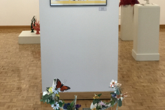 This is a photograph of the 44th annual student art exhibition installation. In this image we are seeing a small section of the rear wall of the gallery with 5 pieces of art installed in the space.