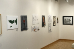 This is a photograph of the 44th annual student art exhibition installation. In this image we are seeing a small section of the left wall of the gallery with 10 pieces of art installed in the space.