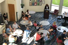 This image shows a group of people sitting at tables, listening to MCC President Dr. Deanna Burt-Nanna speaking during the award ceremony.