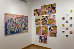 Exhibition installation view of back left corner showing many colorful paintings.