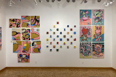 Exhibition installation view showing the rear wall which contains many colorful paintings.