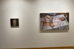 Installation shot of exhibition, a small self portrait is hung on the left, and one large painting of a woman is hanging on the right.