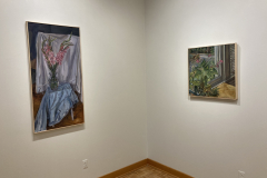 Installation shot of the exhibition, this image shows the rear right corner, containing a painting of flowers on the left and a painting of a potted plant on the right.