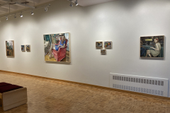 Installation shot of the right wall of the gallery, containing eight paintings of various sizes and subject matter hanging evenly down the wall.