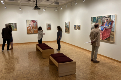 Image from opening reception, shoring the art on the walls and a few small groups of people looking at the artwork and talking.