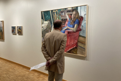 Image from opening reception, shoring the art on the walls and a person looking at the artwork.