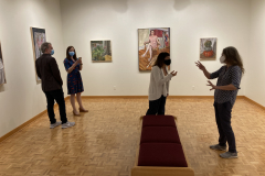 Image from opening reception, shoring the art on the walls and a few small groups of people looking at the artwork and talking.