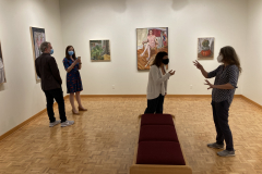 Image from opening reception, shoring the art on the walls and a few small groups of people looking at the artwork and talking.