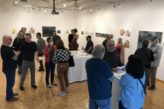 An image from the opening reception, this one is taken inside the gallery showing many people looking at the artwork around the room.