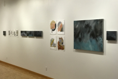This is a photograph showing the inside of the Mercer Gallery. On the wall hangs various artwork including paintings and drawings.
