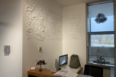 Image showing installation of art in the Mercer Gallery.  Abstract forms on the wall, and hanging outside a window.