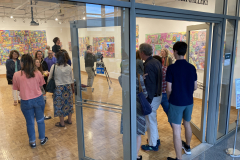 Image of artist opening reception, people gathered in the gallery looking at the art.