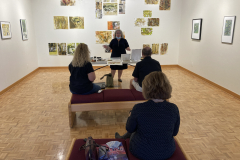 Image of artist giving lecture in gallery, showing examples of how she makes her artwork.