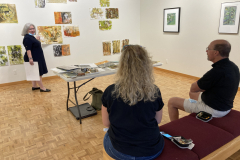 Image of artist giving lecture in gallery, showing examples of how she makes her artwork.