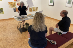 Image of artist giving lecture in gallery, showing examples of how she makes her artwork.